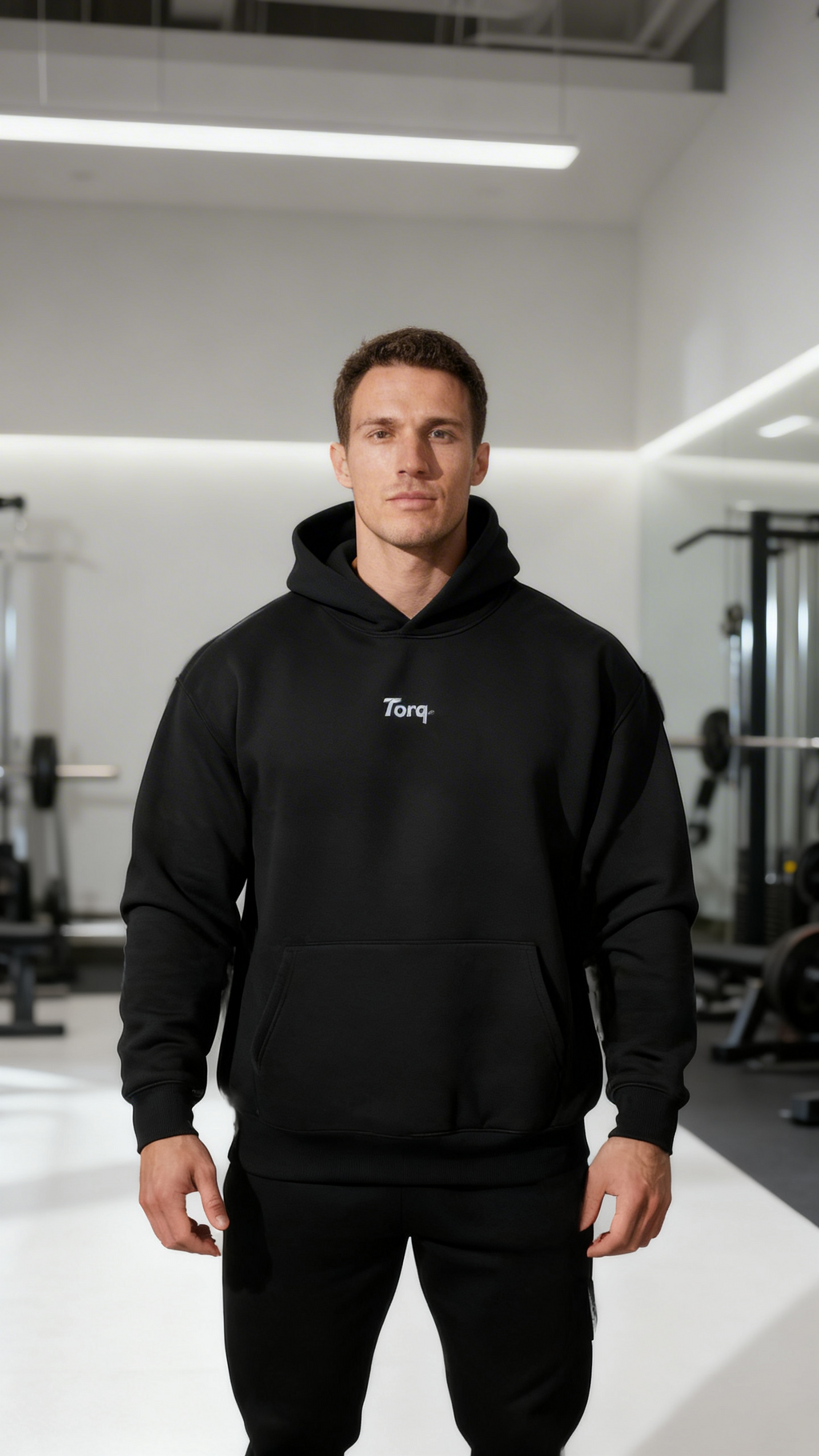 Man wearing a black hoodie with 'Torq' logo in a gym setting